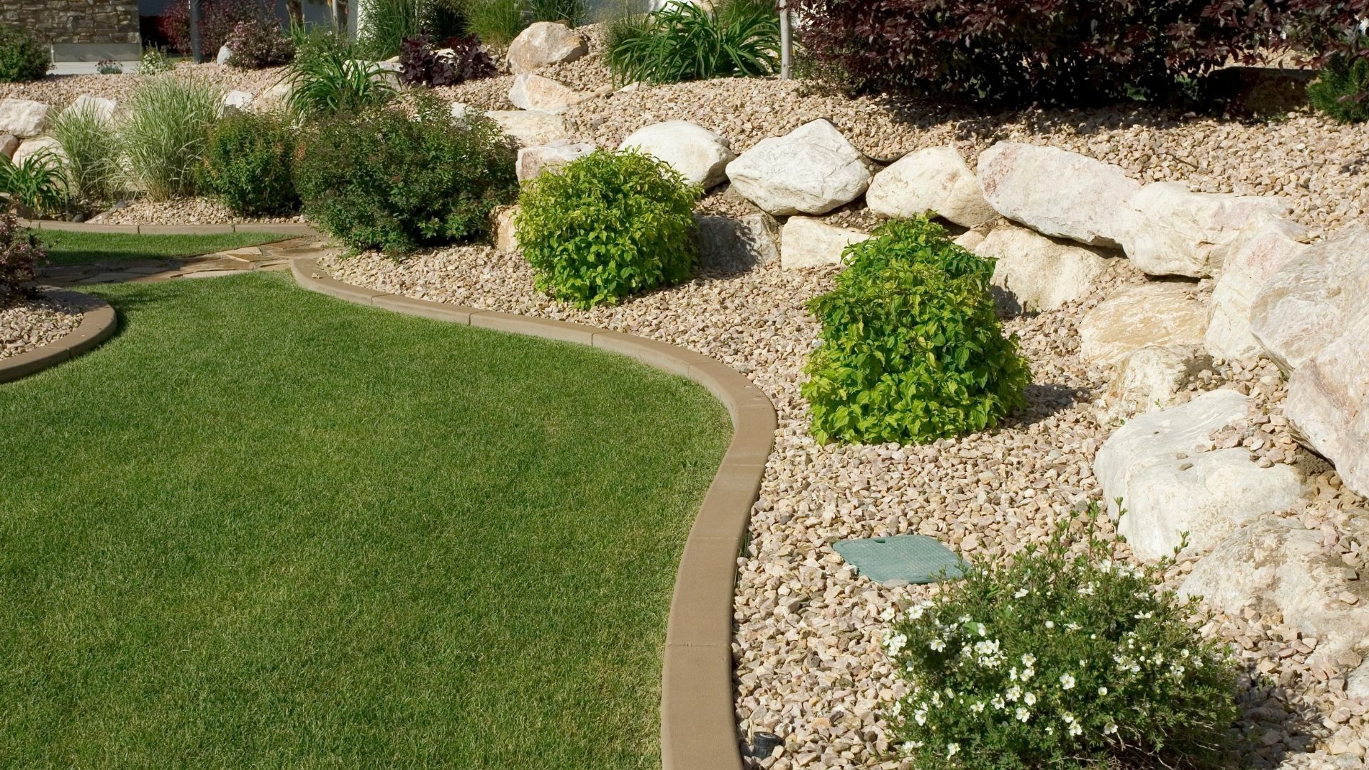 A garden with rocks and grass in front of a house